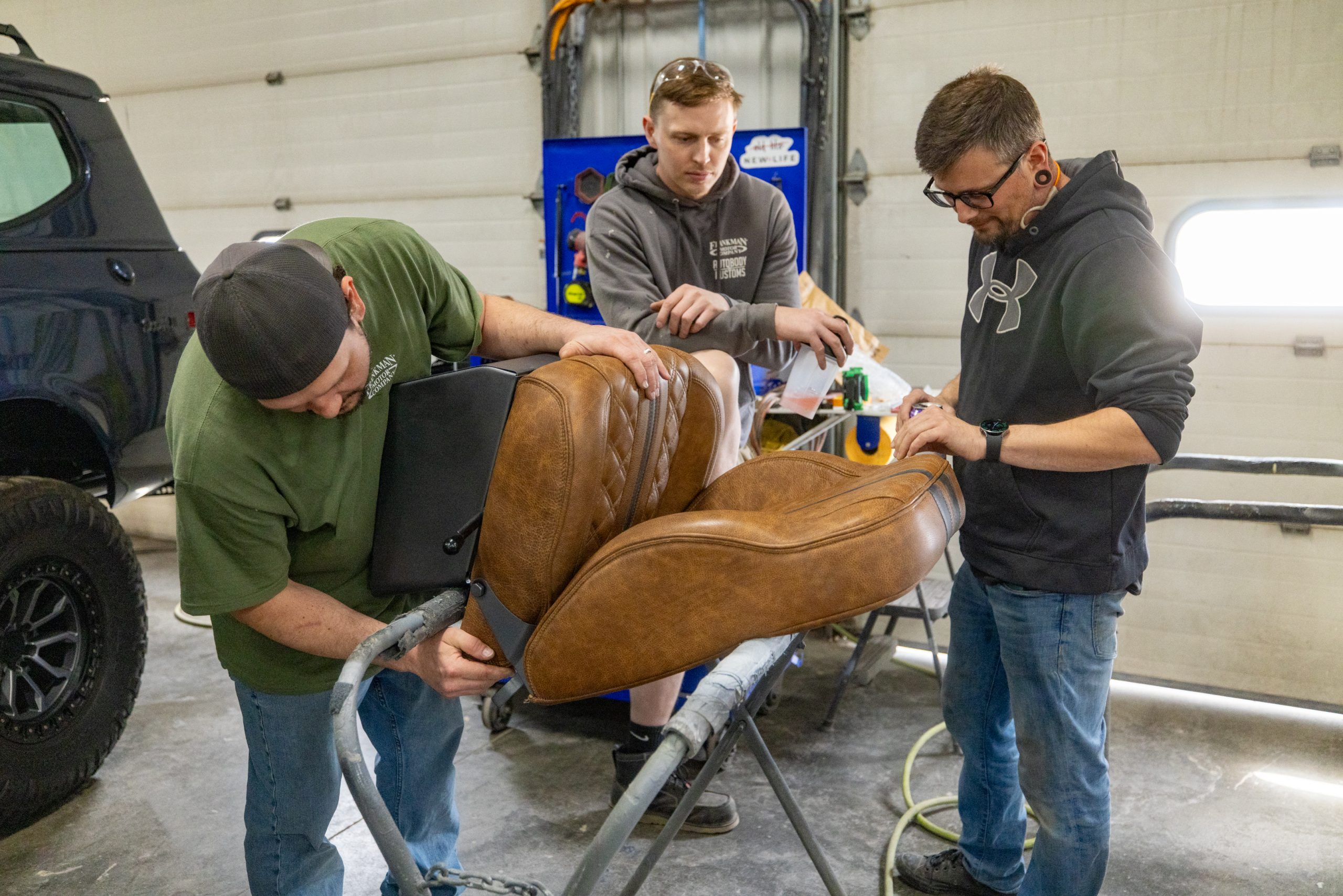 Frankman Motor Company interior team installing custom brown leather seats in a custom International Scout build at the Harrisburg upholstery shop